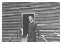 SA0028 - Sarah Collins was from the South Family. She stands in front of an unidentified building door.